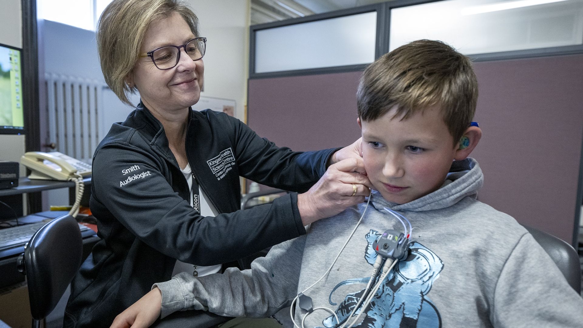 audiologist performs a hearing test on a young patient