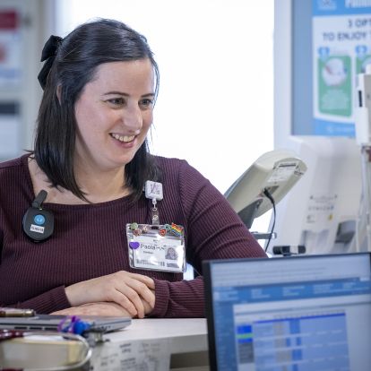 Paola leaning on a counter, speaking to a staff member