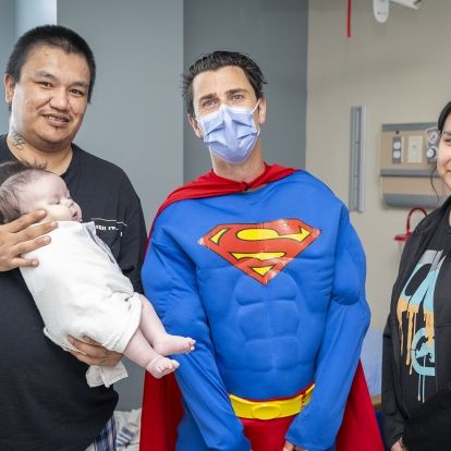 a family introduces their baby to Superman on superhero day at KHSC