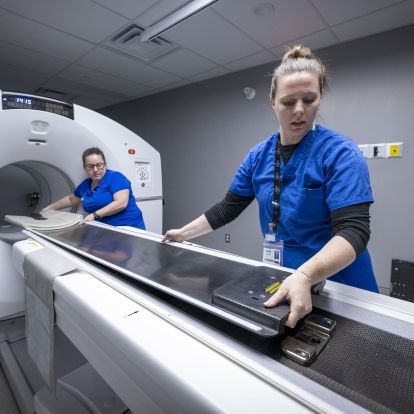 Two KHSC staff prepare the bed of the PET-CT scanner for a patient