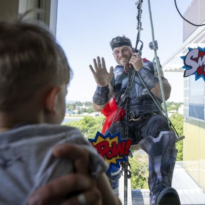 Captain America waves to a young patient at KHSC