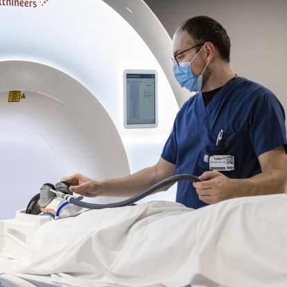 MRI technologist helps a patient put on the MRI goggles