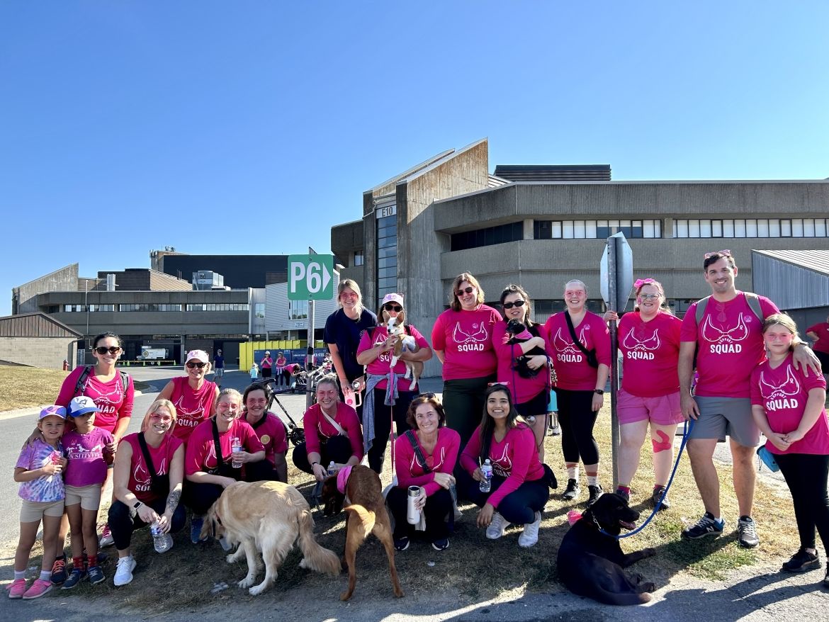 A group of KHSC employees and families wearing pink shirts in a field.