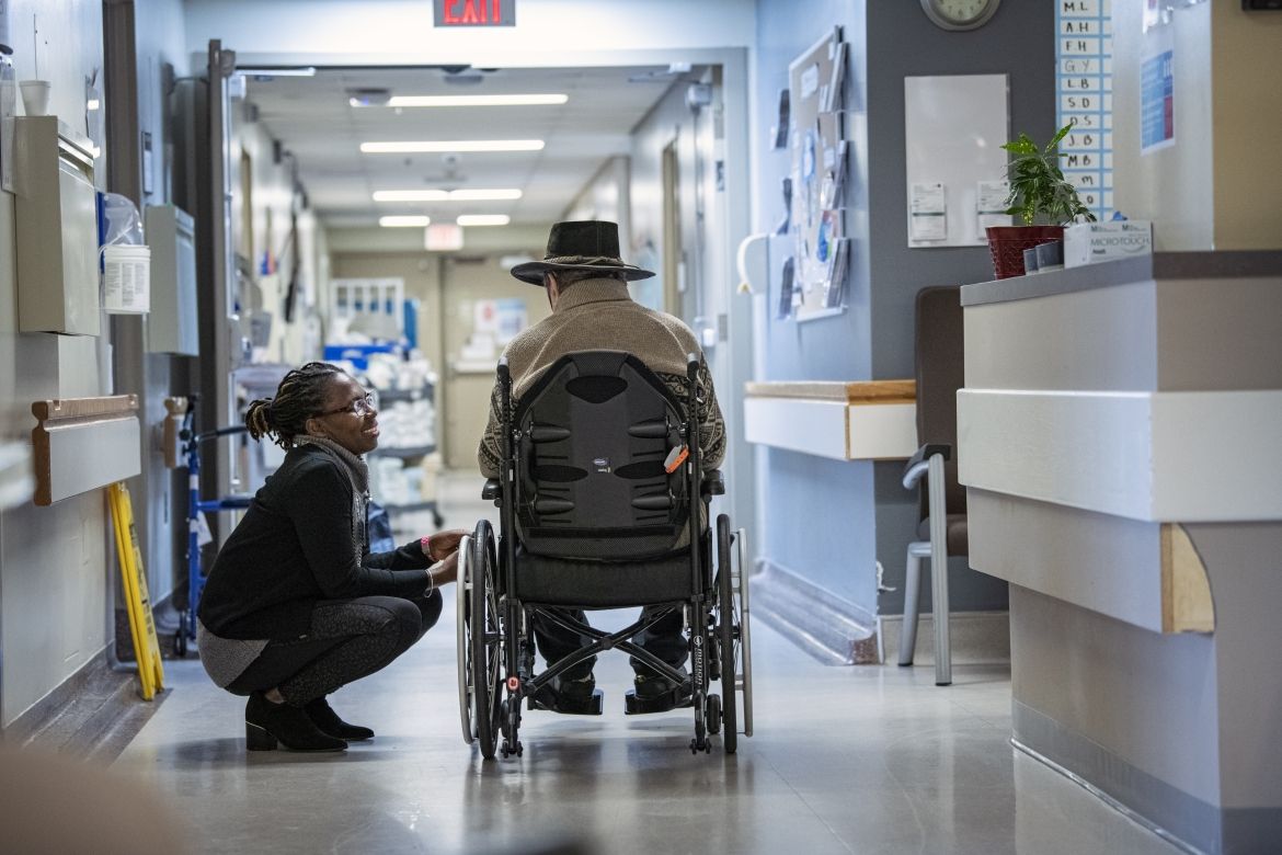 Staff speaking with patient in hospital hallway.