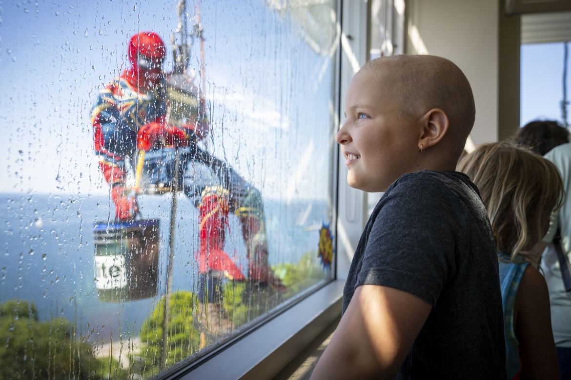 young patient looks on as spiderman cleans window at KGH stie