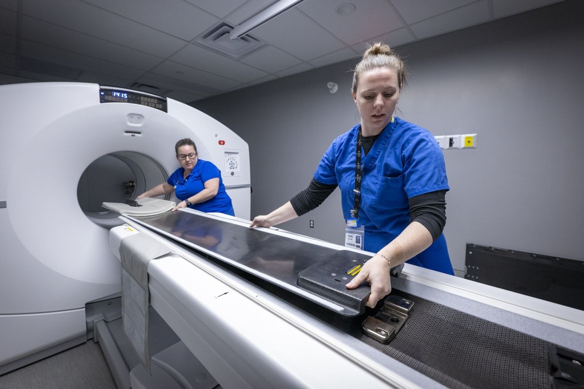 Two KHSC staff prepare the bed of the PET-CT scanner for a patient
