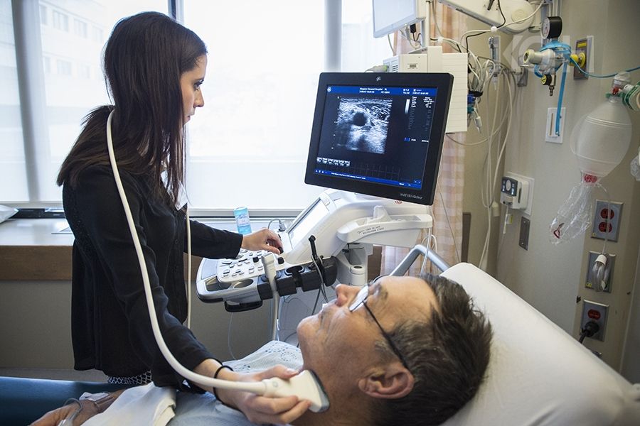 A healthcare practitioner using an ultrasound machine on a patients neck.