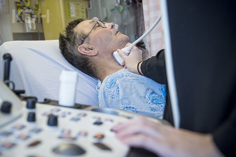 A healthcare practitioner using an ultrasound machine on a patients neck.