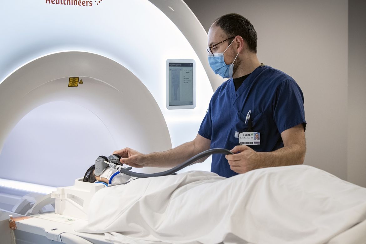 MRI technologist helps a patient put on the MRI goggles