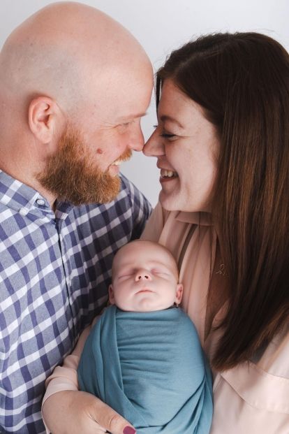 two parents holding a swaddled baby