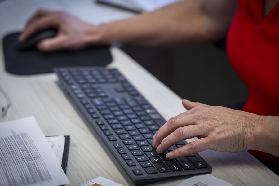 A close up shot of Marianne McKinney’s hands. One is typing on her keyboard, the other is moving her mouse.