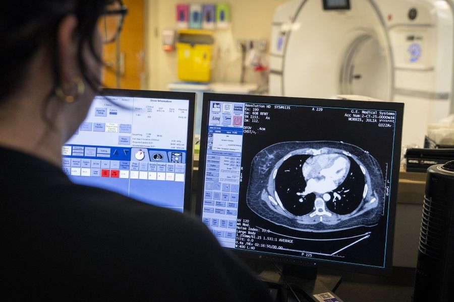 an imaging technician looks at a CT scan