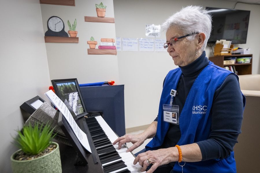A volunteer is sitting and playing a piano.