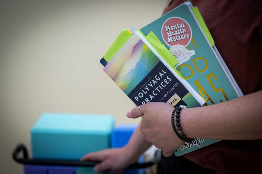 A close up shot of Laurie Hill’s notebooks in her arm. One notebook has a sticker on it that says “mental health matters.”