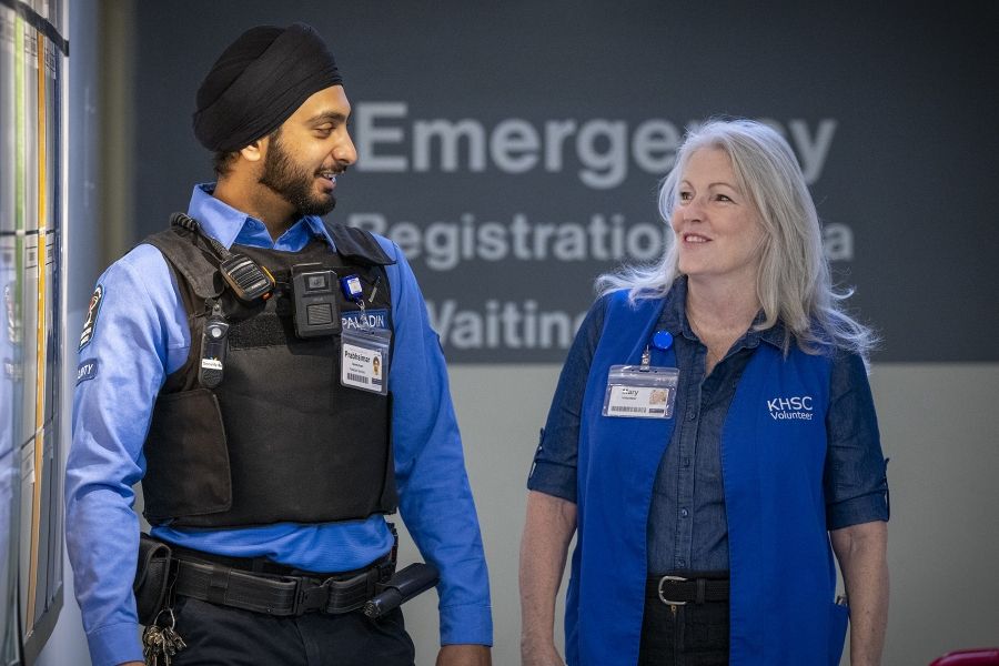 A volunteer and security guard walk down the hallway at KGH.