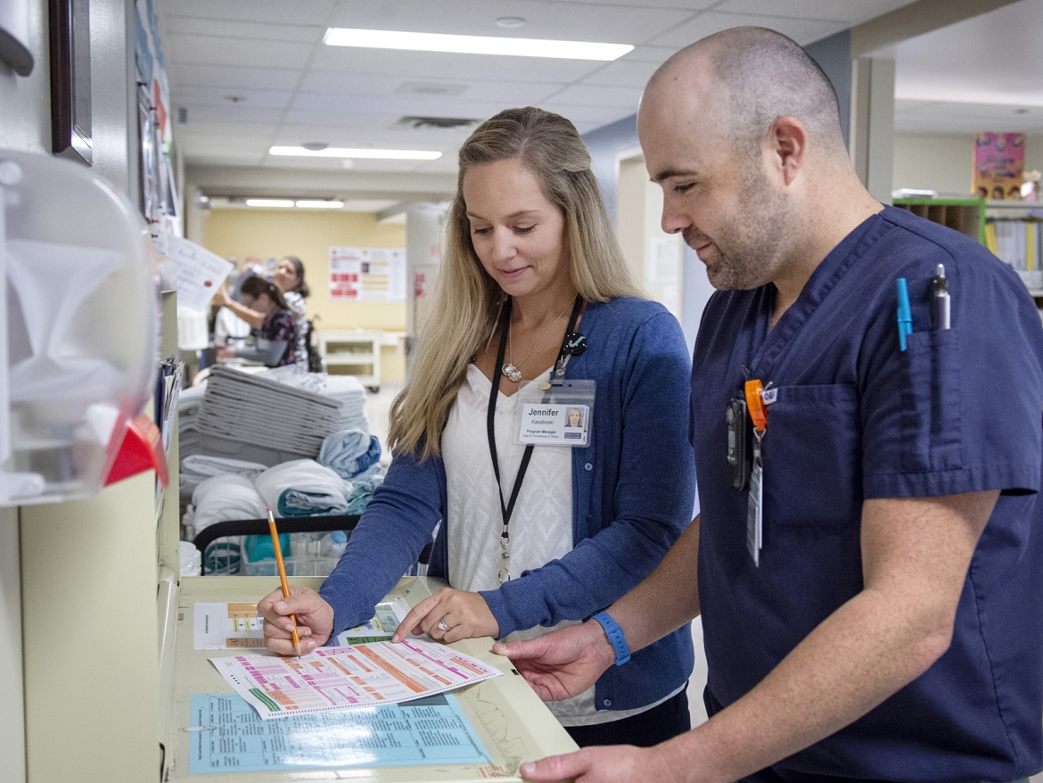 staff on a unit talk together while looking at a patient chart