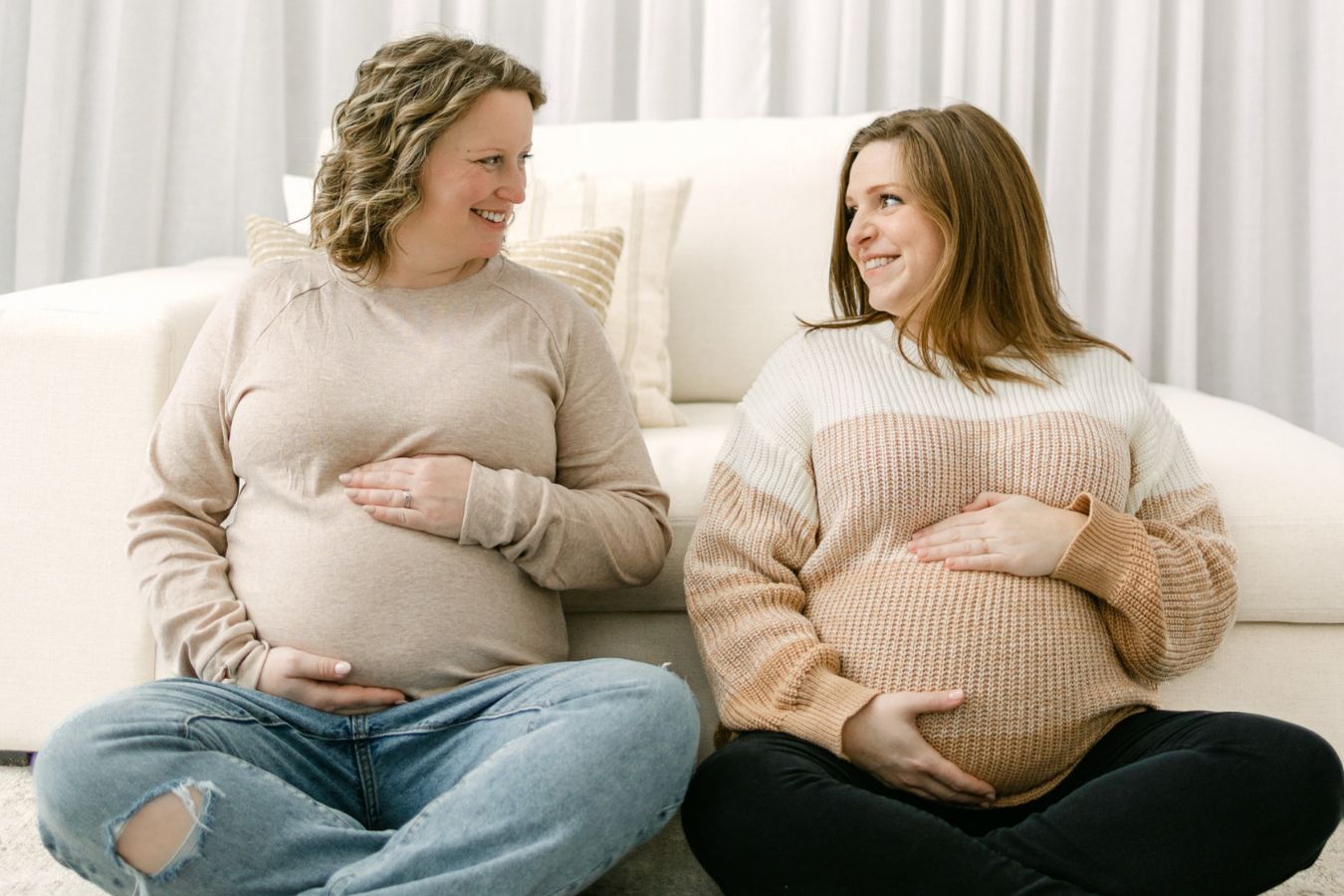 Two pregnant women sit side by side 